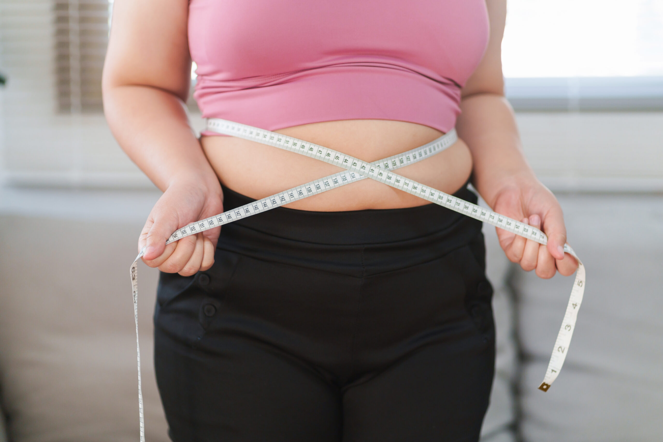 Woman holding measuring tape around waist