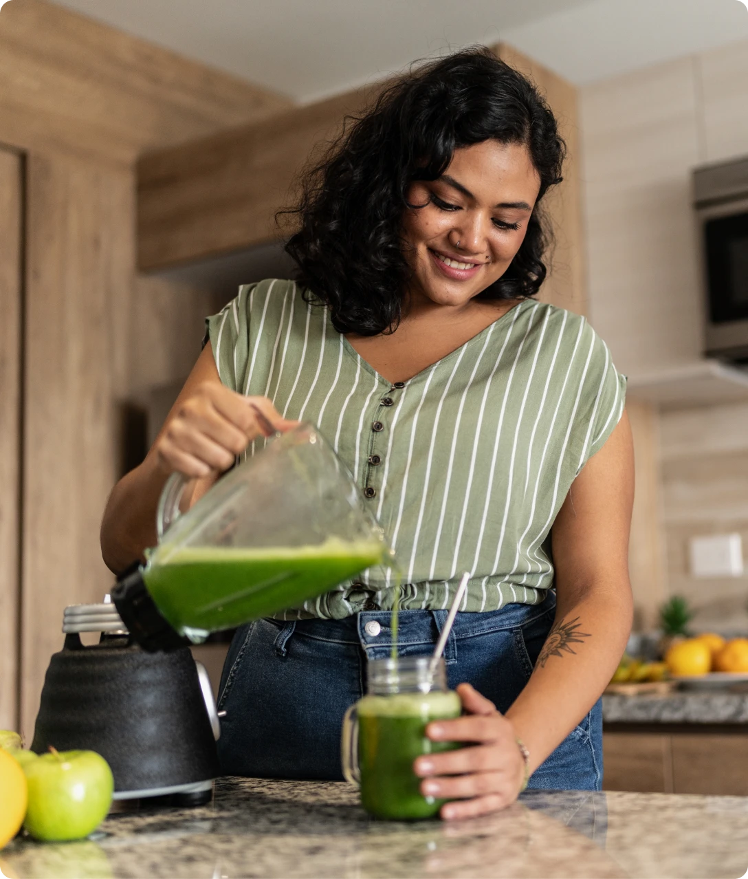 Woman pouring green smoothie into glass