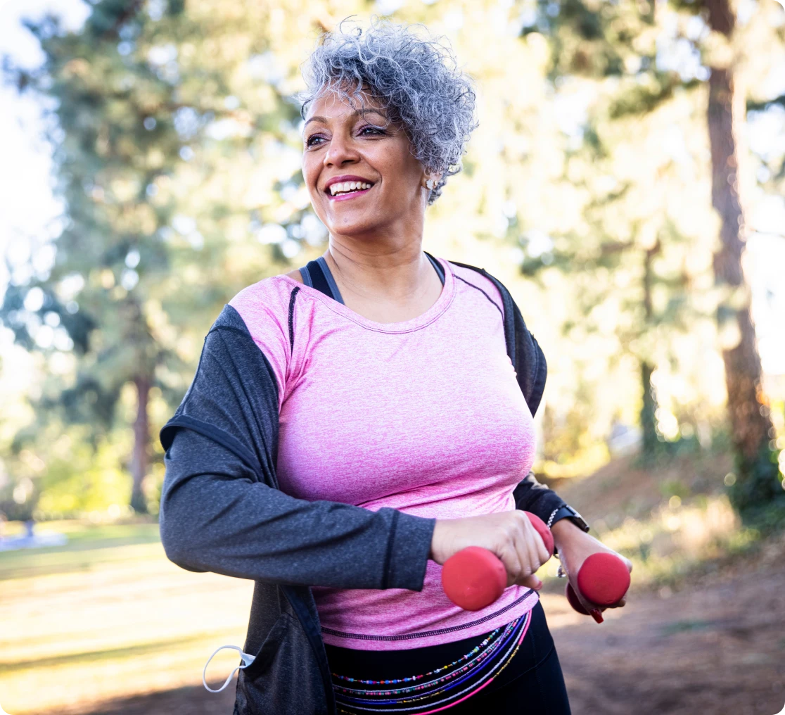 Smiling woman holding red dumbbells